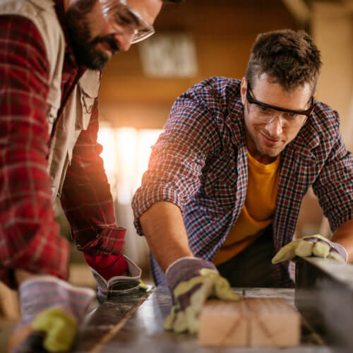 Zwei Kollegen, die gemeinsam an einem Holzbalken arbeiten