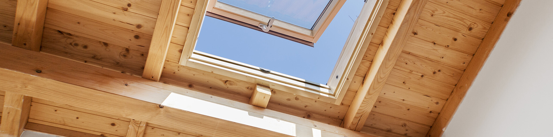 Ein geöffnetes Holzdachfenster mit blauem Himmel