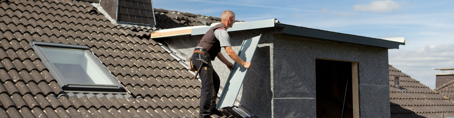 Dachdecker führt Dacharbeiten mit Metallstücken durch