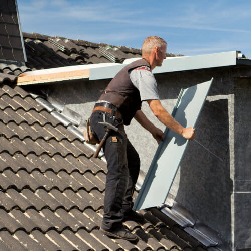 Dachdecker führt Dacharbeiten mit Metallstücken durch