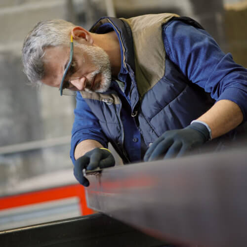 Flaschner bei präziser Metallbearbeitung, trägt Schutzbrille und Handschuhe in moderner Werkstatt